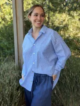 Camisa celeste a rayas verticales blancas, de corte holgado, manga larga y cuello camisero.