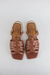 Sandalias de cuero color negro, de suela plana, con tiras entrelazadas en la capellada y tira ajustable en el talón con hebilla metálica.