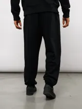 Pantalón jogger de felpa sin frisa, color gris claro melange, con logo bordado de Umbro en azul oscuro en el muslo izquierdo y puños elásticos en los tobillos.