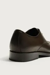 Zapato de vestir tipo derby marrón oscuro, con parte superior lisa y suela con ligero tacón.