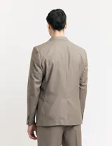 Ambo de corte clásico compuesto por saco de dos botones y pantalón de vestir a juego. El saco cuenta con solapas de muesca, bolsillos laterales con solapa y un bolsillo en el pecho. El pantalón presenta un corte recto y limpio.