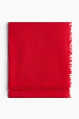 Bufanda grande de tejido suave y cálido en color rojo, con superficie levemente cepillada y acabado desflecado en los bordes.