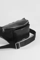 Riñonera de cuero sintético color blanco marfil, con doble bolsillo frontal con cierre metálico a contraste y correa ajustable.