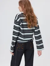 Remera de manga larga con diseño a rayas horizontales en tonos azul, blanco y negro. Presenta un cuello redondo al tono y un logo bordado en el pecho. El diseño destaca por tener un patrón de rayas diferente en las mangas y un calce holgado.