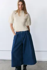 Jeans de tiro medio con diseño culotte y pierna ancha. Presenta cinco bolsillos, detalle de pinzas en el delantero y cierre frontal con cremallera y botón metálico.