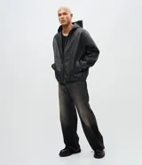 Chaqueta masculina de poliuretano color negro, con diseño de capucha, cierre frontal completo y puños elásticos. Presenta un acabado liso y estructura robusta.