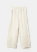 Pantalón palazzo color blanco con detalles bordados en el bajo de las piernas, tiro medio y cintura elástica con cordón ajustable.