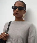 Suéter de punto color negro con cuello redondo y mangas largas. Presenta un diseño con franjas horizontales decoradas con lentejuelas del mismo tono en el cuerpo y las mangas.