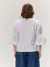 Remera blanca con cuerpo de algodón liso y mangas abullonadas semitransparentes con textura de lunares.