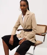 Blazer sastre color beige, de corte estructurado y calce al cuerpo, con solapa clásica, bolsillos con solapa en los laterales, bolsillo superior y cierre frontal de un botón.