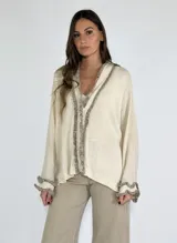 Saco color crudo de tejido de punto con detalle de volados en el frente y en los puños.