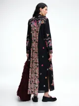 Vestido camisero largo de algodón negro con cuello camisero, cierre frontal de botones y mangas largas. Presenta un diseño con bordados florales coloridos a lo largo de toda la prenda.