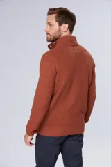 Buzo de tejido grueso color gris, con cuello alto y cierre frontal parcial. Presenta puños y ruedo acanalados, con un diseño de textura tejida en toda la prenda.