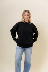 Sweater de tejido fino color beige, con cuello redondo, mangas largas y terminaciones acanaladas. Presenta un diseño con detalles trenzados en diagonal en el frente y corte relajado.