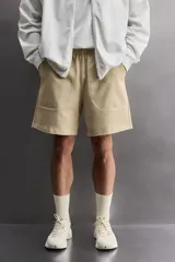 Short jogger marrón de corte relaxed fit, confeccionado en tejido compacto de algodón, con cintura elástica ajustable, bolsillos frontales en la cadera y bolsillo trasero de plastrón.