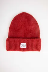 Gorro de lana tejido color rojo con etiqueta blanca con texto en el dobladillo.