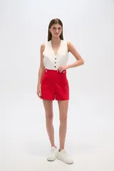 Short de lino color beige, de tiro alto y corte holgado. Presenta bolsillos frontales amplios y detalle de botones decorativos en la cintura.