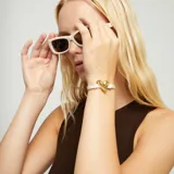 Pulsera ajustable con cordón blanco y dije central de corazón martillado con baño dorado. Incluye una cuenta redonda marrón como tope ajustable.