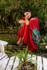 Capullo o kimono de paño 100% algodón, color rojo con estampado exclusivo en tono verde, de morfología amplia y envolvente, con bolsillos laterales y cinto independiente para ajustar la cintura.