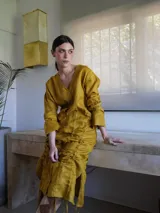 Vestido corto de lino rojo con escote en V, mangas largas y sistema de jaretas ajustables con cordones frontales para fruncir y regular el largo.