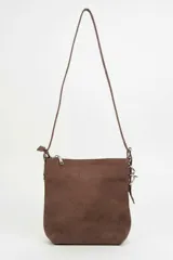 Cartera de hombro color marrón, con textura de gamuza, cierre de cremallera y detalle de argollas metálicas en el lateral.