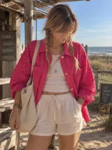Sobrecamisa fucsia con diseño calado, mangas largas abullonadas, bolsillos frontales con solapa y cierre con botones metálicos.