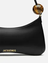 Bolso de hombro Jacquemus Le Bisou Perle, estructurado en piel lisa negra, con correa de hombro ajustable decorada con ab cuentas grandes efecto carey. Incluye logotipo metálico dorado en la parte frontal y herrajes metálicos a juego.
