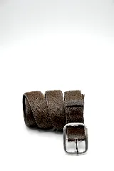 Cinturón de cuero con pelo en tono oscuro, con hebilla metálica plateada de diseño rectangular.