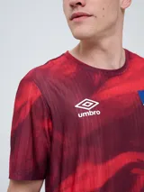 Remera de entrenamiento Umbro del Club Nacional de Football, modelo Press, para hombre. Diseño en tonos de rojo con patrón estampado tipo humo o abstracto, cuello redondo y mangas cortas. Incluye el logo de Umbro y el escudo del club en el pecho.