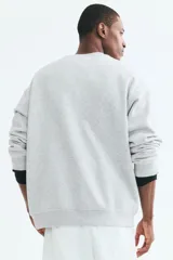Buzo de cuello redondo color gris melange, de corte holgado, con hombros caídos y puños y dobladillo acanalados.