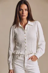 Camisa blanca de manga larga con diseño fruncido tipo nido de abeja en el frente y la espalda, cuello camisero, cierre frontal con botones y pequeño volante en el ruedo.