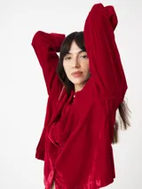 Camisa corta negra de terciopelo, de silueta cuadrada oversized, con bolsillo delantero y detalle en los puños y cuello con botón oro en forma de flor.