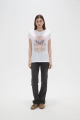 Remera de algodón blanca con estampado frontal de mariposa y texto decorativo en tonos pasteles, de manga corta con dobladillo y calce holgado.