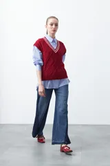 Chaleco de punto color bordó, con diseño de rombos y trenzas en relieve. Escote en V con ribete blanco y rojo.