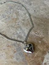 Collar corto de cadena plateada con dije de corazón tridimensional y brillante.