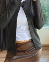 Minifalda negra de efecto cuero con tiro alto y corte ligeramente acampanado.