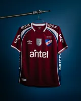 Camiseta de fútbol Umbro de golero del Club Nacional de Football, modelo oficial 2026. Diseño en color bordó con textura y detalles en blanco y azul en cuello, hombros y laterales. Cuenta con cuello en V, escudo del club, logo de Umbro y los sponsors oficiales estampados en el frente y las mangas.