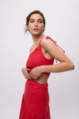 Vestido azul con bretel fino, escote asimétrico de un hombro, corte a la cintura con recorte en el lateral y falda midi con volados irregulares.