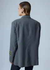 Saco sastrero oversize gris con bolsillos delanteros, forro de tafeta a tono, bordado en la tapa del bolsillo y etiqueta RENÉE tejida.