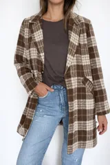 Chaqueta larga de corte recto con estampado de cuadros en tonos marrones y beige. Presenta cuello con solapas, cierre frontal con un botón y bolsillos laterales funcionales. Incluye forro interior.