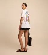 Remera blanca alargada de algodón, con cuello redondo y mangas cortas. Presenta una estampa grande en la espalda con iconos de la cultura brasileña.