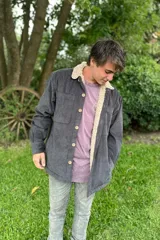 Campera de pana gris con interior de corderito color crema, cierre con botones a presión y bolsillos frontales.