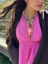 Collar corto con cuentas de cerámica y acrílico de colores, tiento sintético y dije de resina en forma de hoja de palmera color coral.