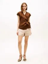 Blusa cruzada sin mangas de lino color marrón, con cuello en V, cuello inglés y lazo anudable en el lateral.