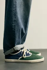 Zapatilla casual de hombre con diseño combinado en color naranja y marrón oscuro, con cordones y suela de goma en contraste.