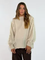 Sweater de punto color negro, con cuello redondo, mangas largas abullonadas y detalles de flecos en las costuras de los hombros y mangas.