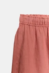 Pantalón confeccionado en lino 100%, de tiro medio con cintura elástica ajustable mediante cordones y bajo redondeado con aberturas laterales.
