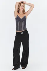 Pantalón cargo de tiro medio confeccionado en tejido satinado. Presenta bolsillos laterales con solapa, corte recto y holgado, y un cinturón integrado del mismo tejido con hebilla metálica.