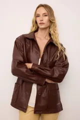 Chaquetón de cuero oversized color marrón, con corte recto, cuello camisero y cierre frontal de botones. Presenta bolsillos delanteros con bordados inspirados en la costa atlántica.