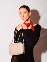 Bandolera de cuero natural con diseño acolchado en forma de rombos. Cuenta con una correa de cadena metálica entrelazada con cuero, cierre superior y herrajes metálicos.